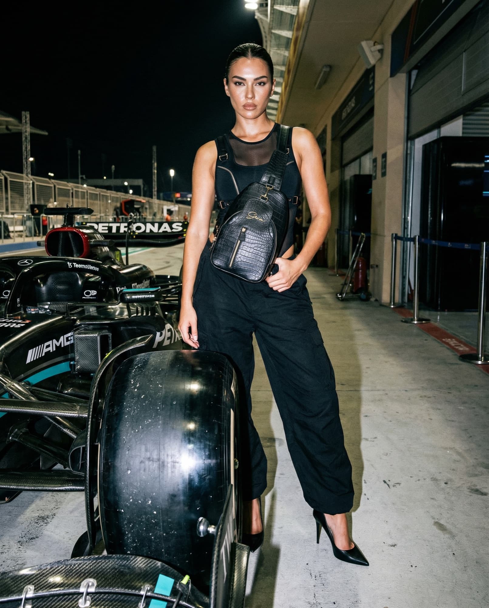 Black GENA sling bag worn crossbody in an F1 pit lane