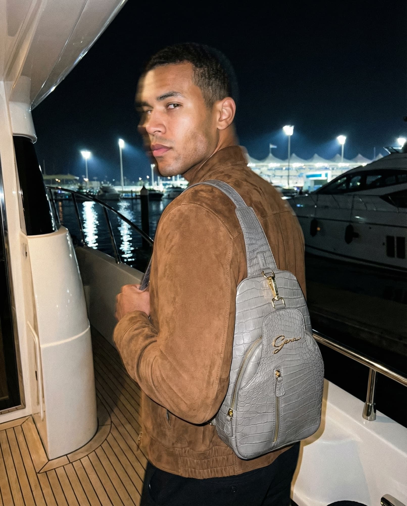 Gray sling bag carried aboard a yacht at night